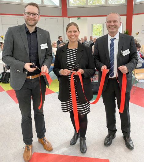 Regionalentwicklungsministerin Osigus eröffnet mit Frederik Brandt und Bernd Retzki das Regionale Versorgungszentrum in Baddeckenstedt. Sie halten ein durchschnittenes Band in der Hand. Im Hintergrund Publikum zu sehen.