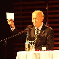 Staatssekretär Wolfgang G. Gibowski zeigt die Karte mit der Stellenanzeige hoch